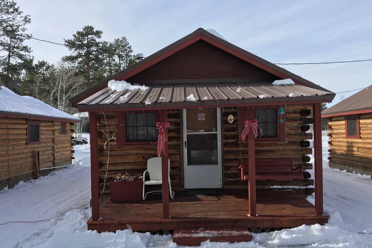 A log cabin with a porch, a chair, and a small table.