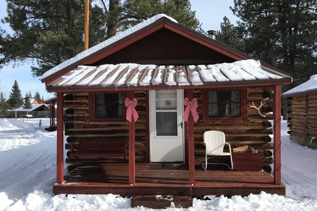 A log cabin with a snow-covered roof and a porch.