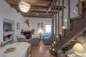 Un'atmosfera rustica con una scala in legno, un tavolo da pranzo con un gioco da tavolo, un divano e una televisione.