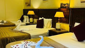 A hotel room with two beds, each with a headboard, bedside lamps, and pillows. There is a decorative swan on the bed in the foreground.