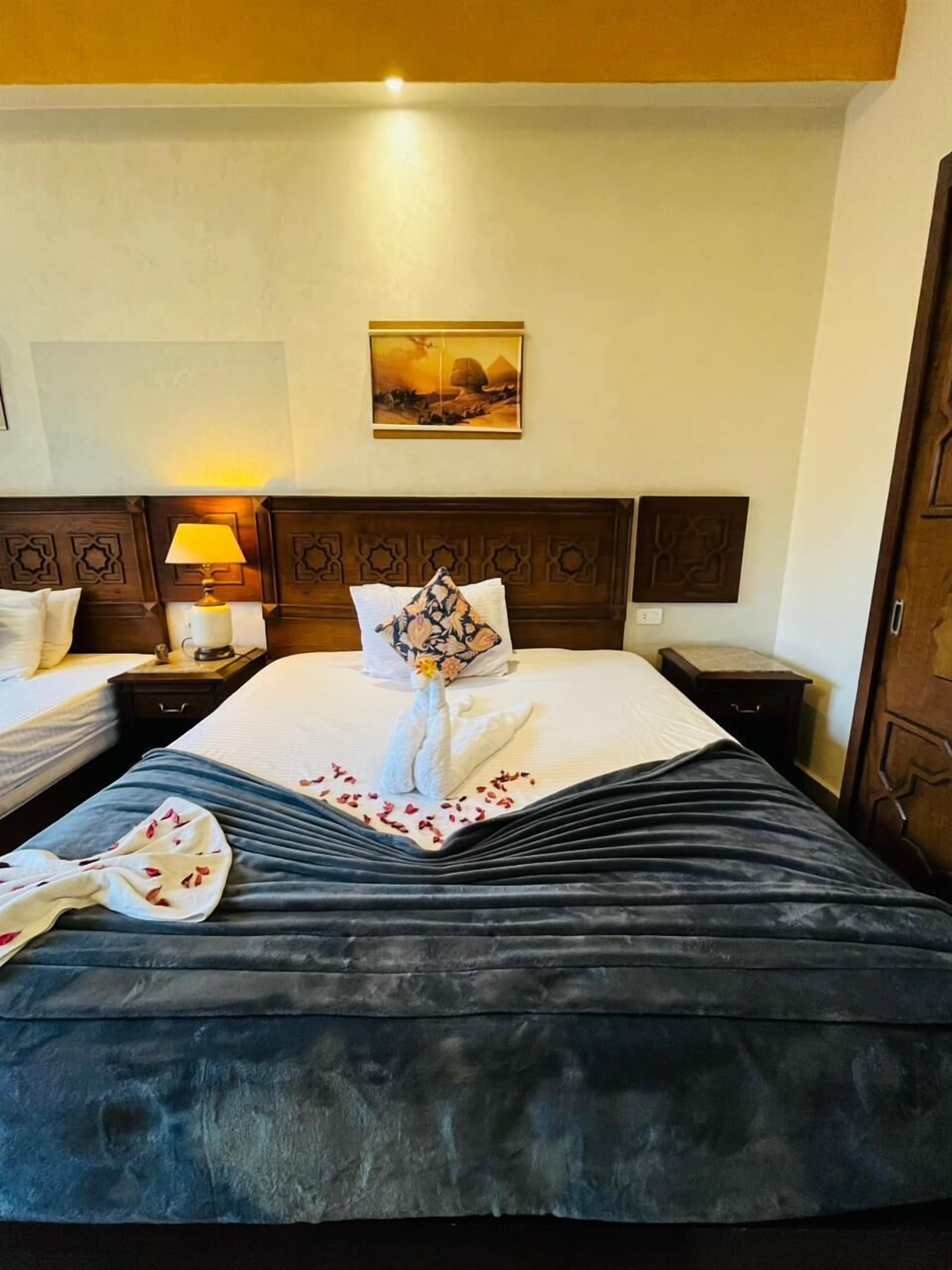 Habitación de hotel con una cama grande, dos mesitas de noche, una lámpara y un cuadro en la pared.