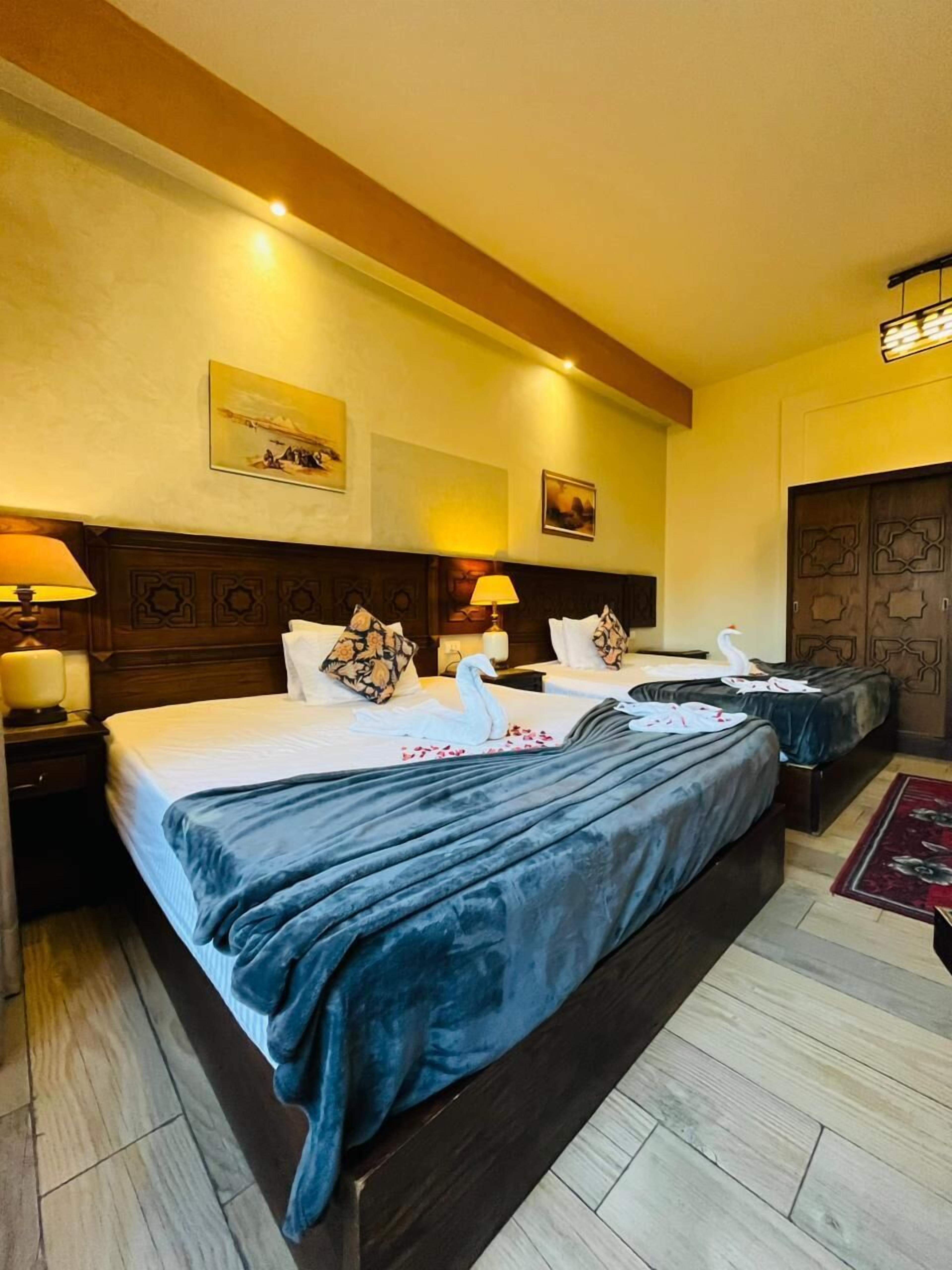 A hotel room with a large bed, two bedside tables, a nightstand, and a wooden wardrobe.