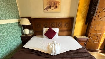 Habitación de hotel con una cama grande, una mesita de noche, una lámpara, un panel decorativo en la pared y un cuadro enmarcado.