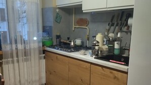 A kitchen with wooden cabinets, a stove, and various kitchen utensils.