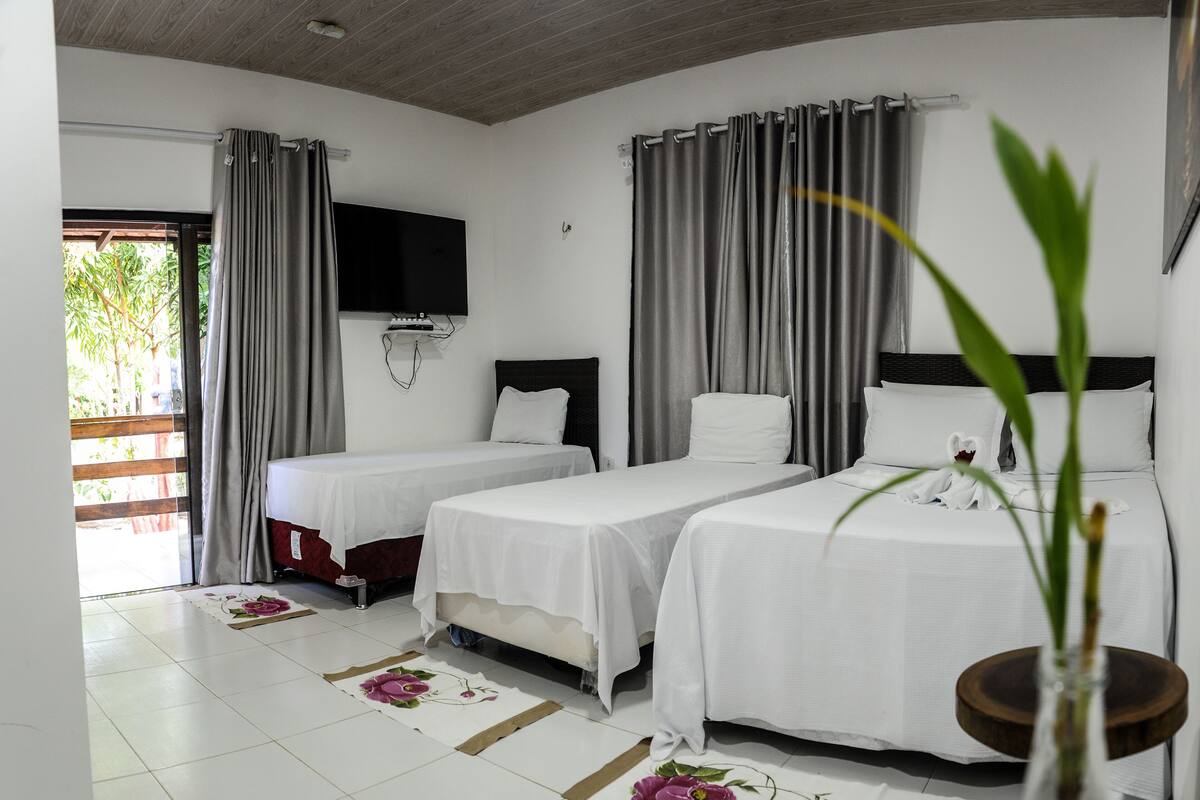 A hotel room with two beds, a TV mounted on the wall, and a large window with curtains.