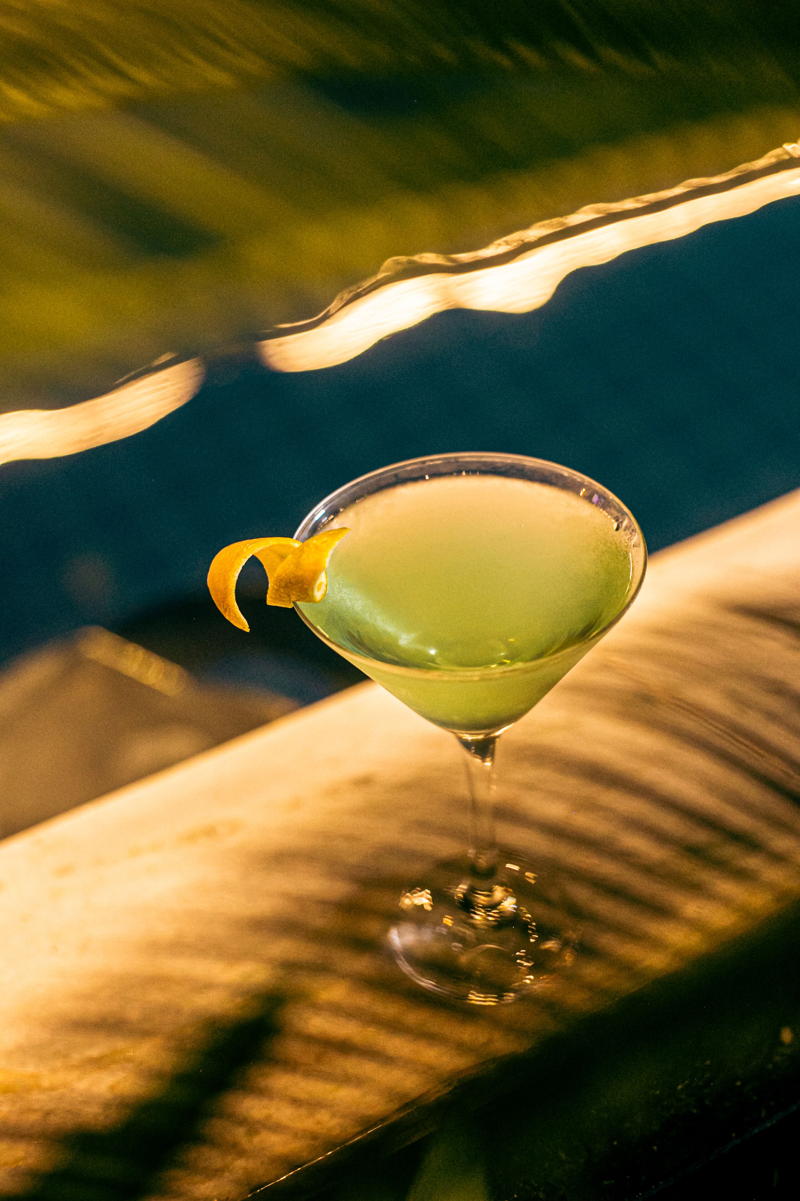 Ein Martini-Glas mit Zitronenzeste auf einer Holztresen.