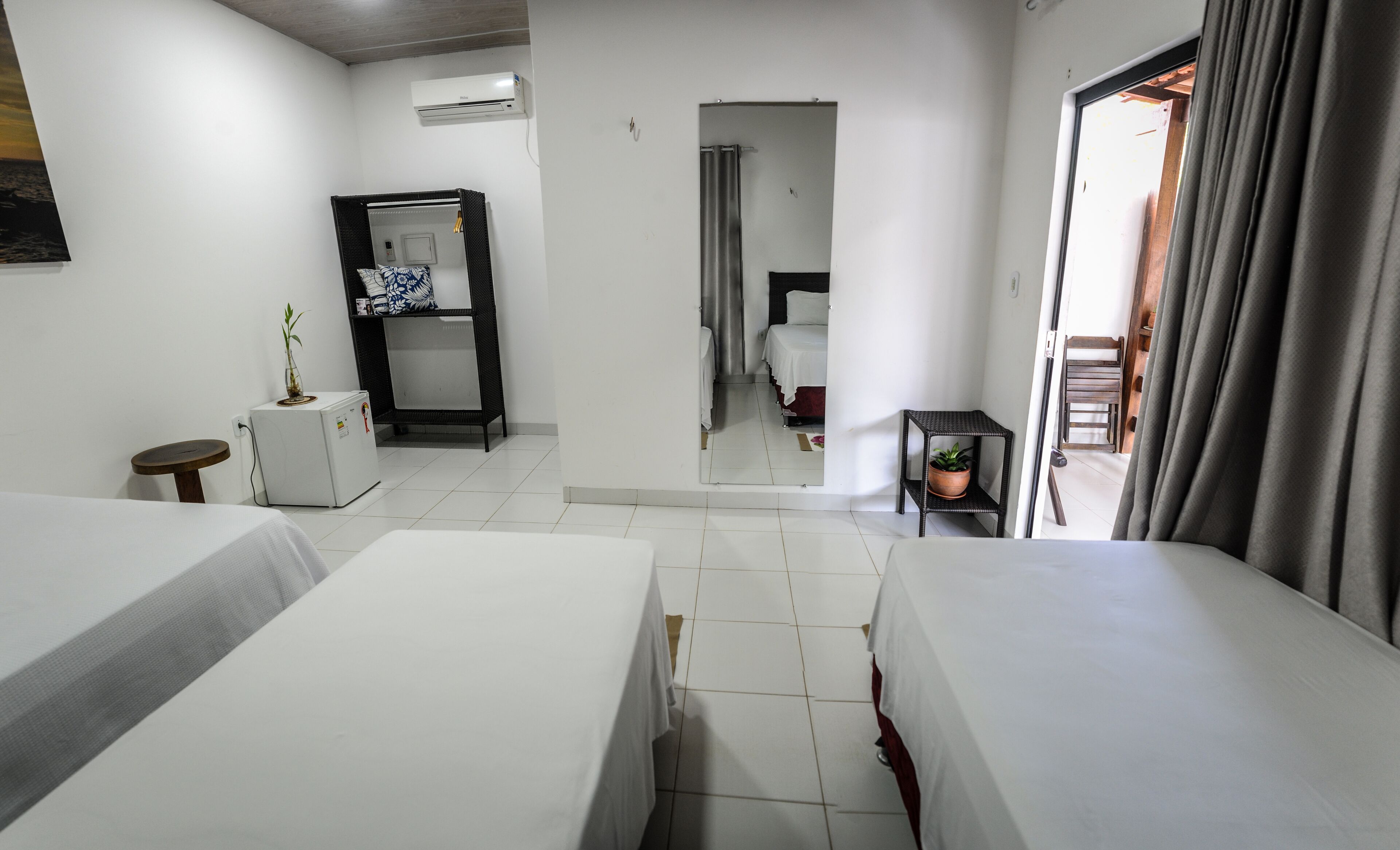 A hotel room with two beds, a small table, a potted plant, and a wardrobe.