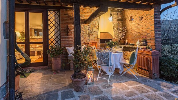An outdoor patio with a brick wall, a stone floor, and a table set for dining. - ROSYABATE COTTAGE with Private Garden and views between Lucca and Pistoia (Uzzano)