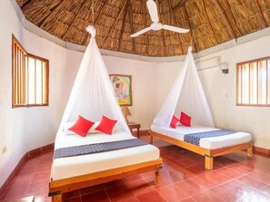 Two beds with mosquito nets, a ceiling fan, and a painting on the wall. - Villas del Angel (Valladolid)