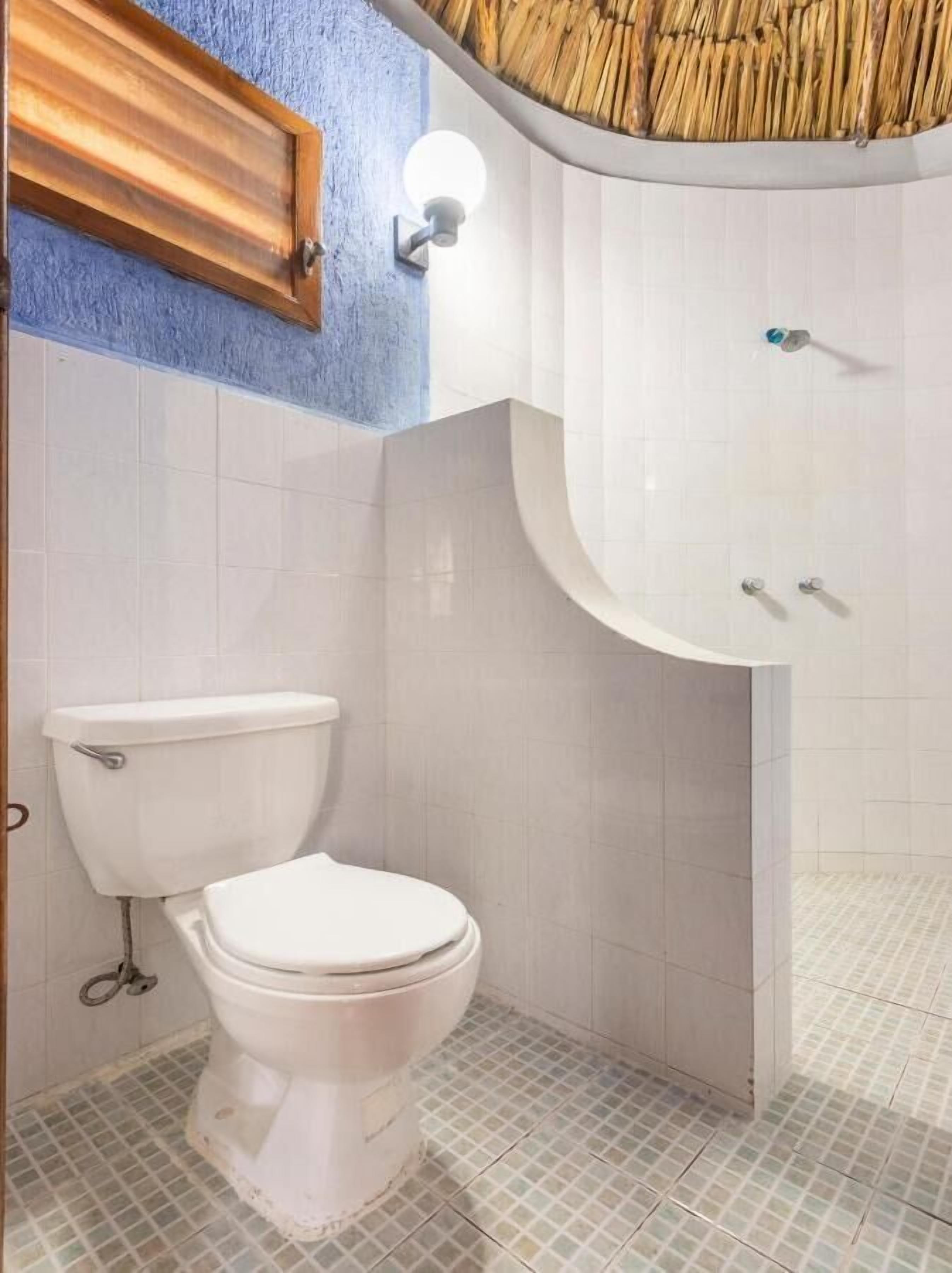 A bathroom with a white toilet, a sink with a curved countertop, and a wall-mounted light fixture.