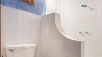 A bathroom with a white toilet, a sink with a curved countertop, and a wall-mounted light fixture.
