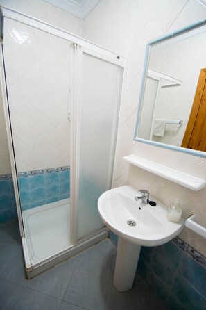 A bathroom with a white sink, a mirror, and a shower enclosure.