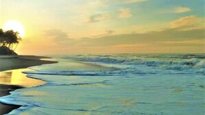 A beach with waves, a sunset, and a distant tree line. - Ardeen Villa (Kahandamodara)
