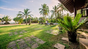 A tropical garden with palm trees, a pool area, and a covered seating area. - Ardeen Villa (Kahandamodara)