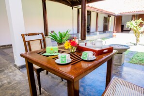 A wooden table with two green tea cups, a red flower, and a potted plant. - Ardeen Villa (Kahandamodara)