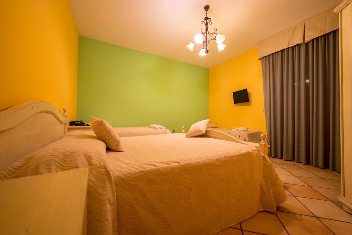 Ein Hotelzimmer mit zwei Betten, einem Fernseher und einem Vorhang.