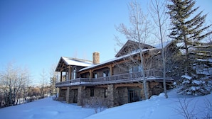 A large stone building with a balcony, surrounded by snow-covered trees.