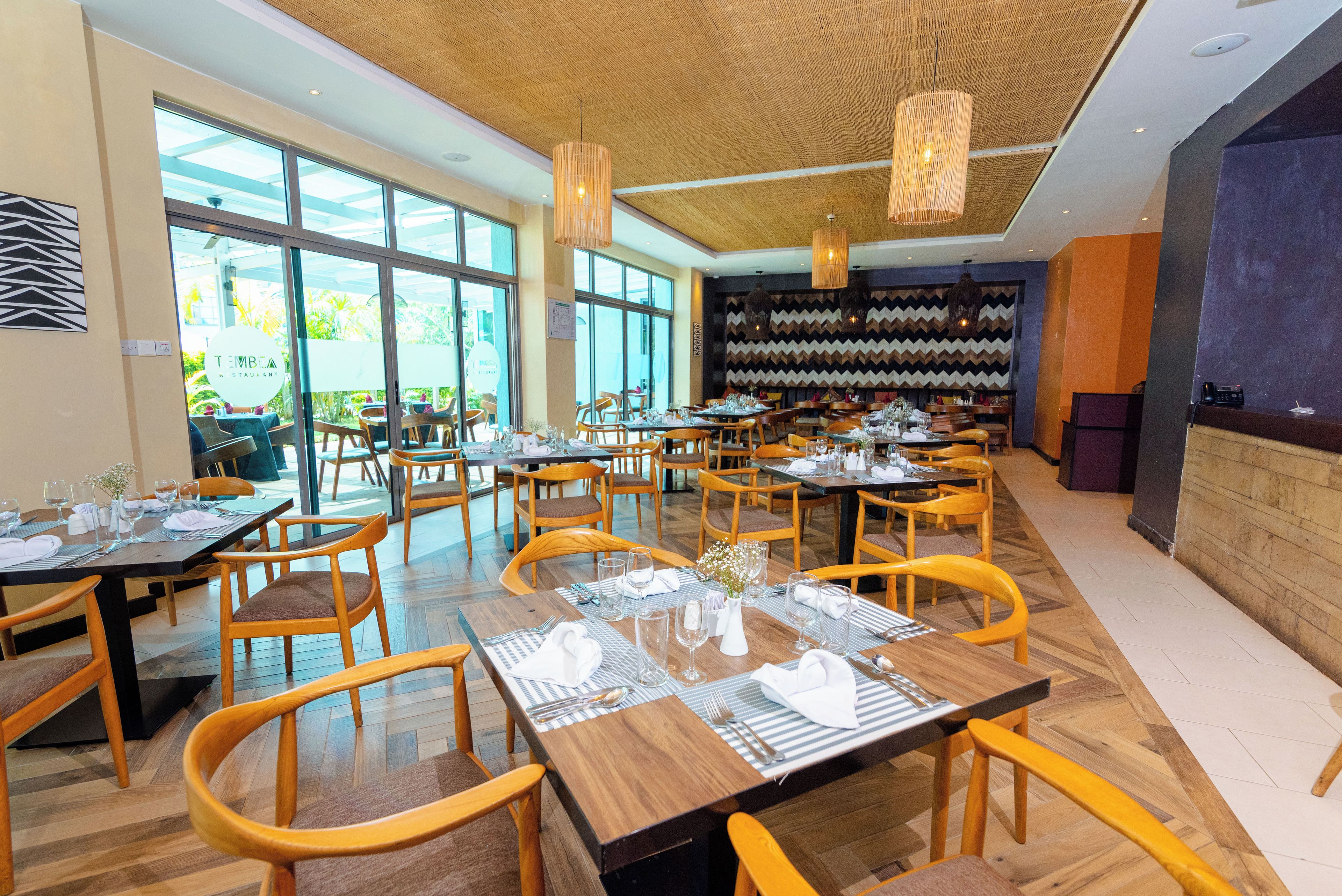 A restaurant with multiple tables, chairs, and hanging lights.