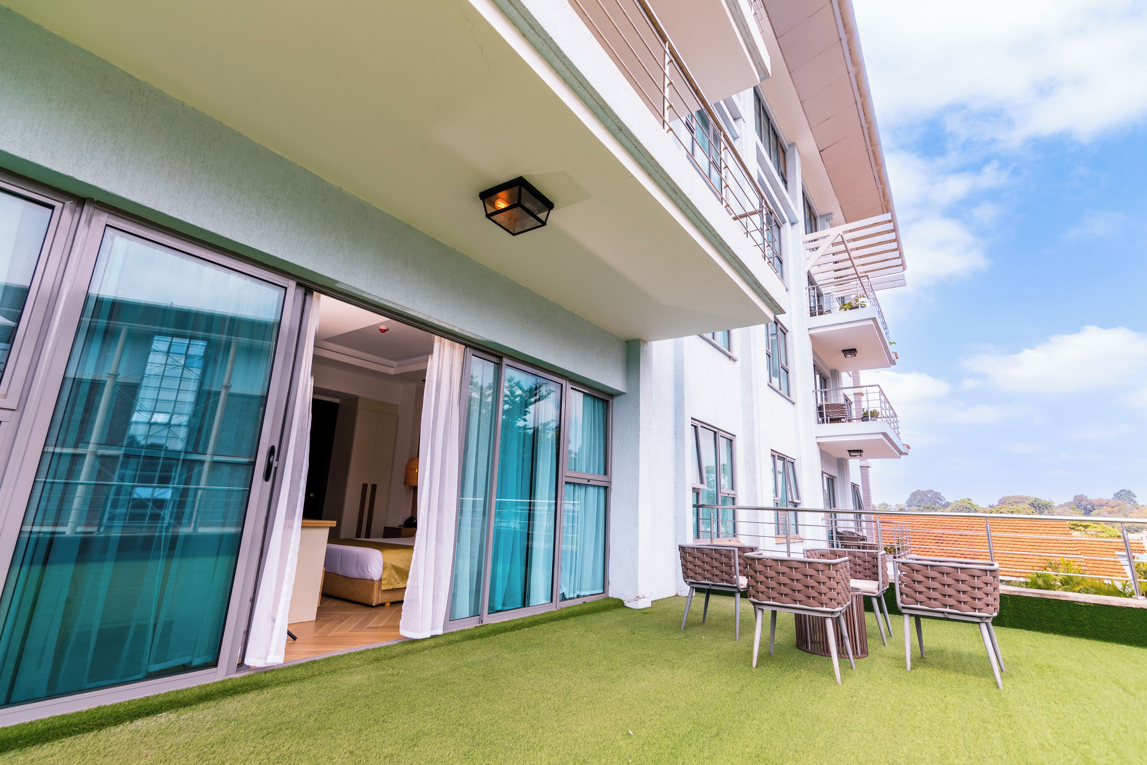 Un edificio moderno con balcón, mobiliario exterior y vistas al cielo.