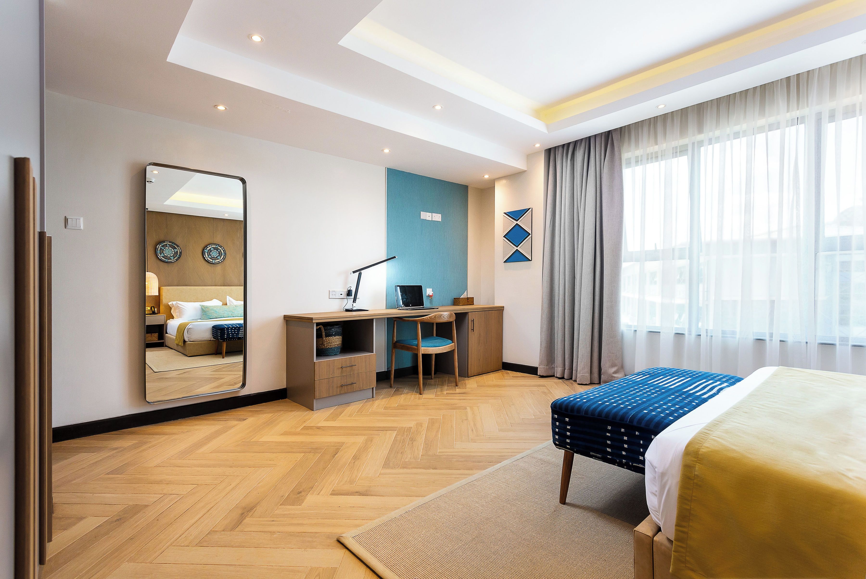 Habitación de hotel con cama, escritorio, silla y un espejo grande.