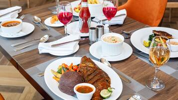 A dining table with a variety of dishes, including a whole fish, vegetables, and a bowl of soup.