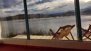A view from a window overlooking a lake with mountains in the background. - Uros Quechua Lodge (Puno)