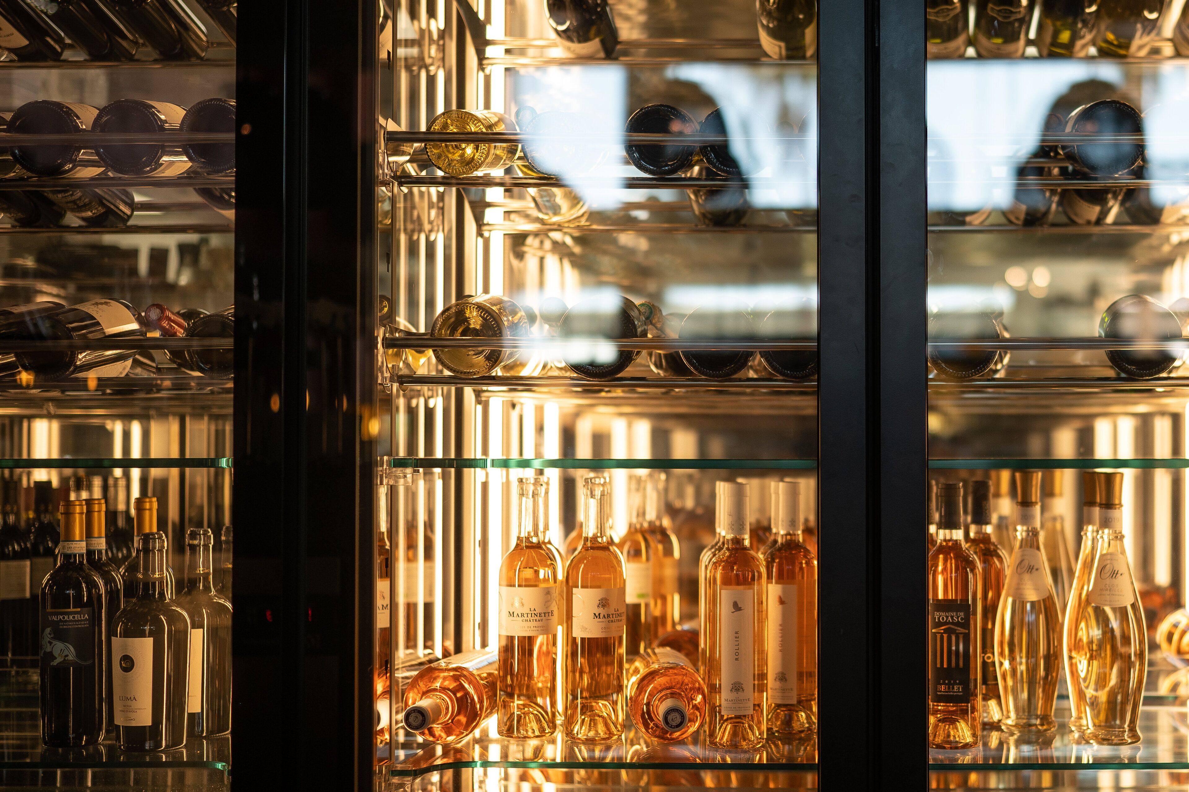 A display of various bottles, likely containing alcoholic beverages, arranged on shelves in a well-lit area.