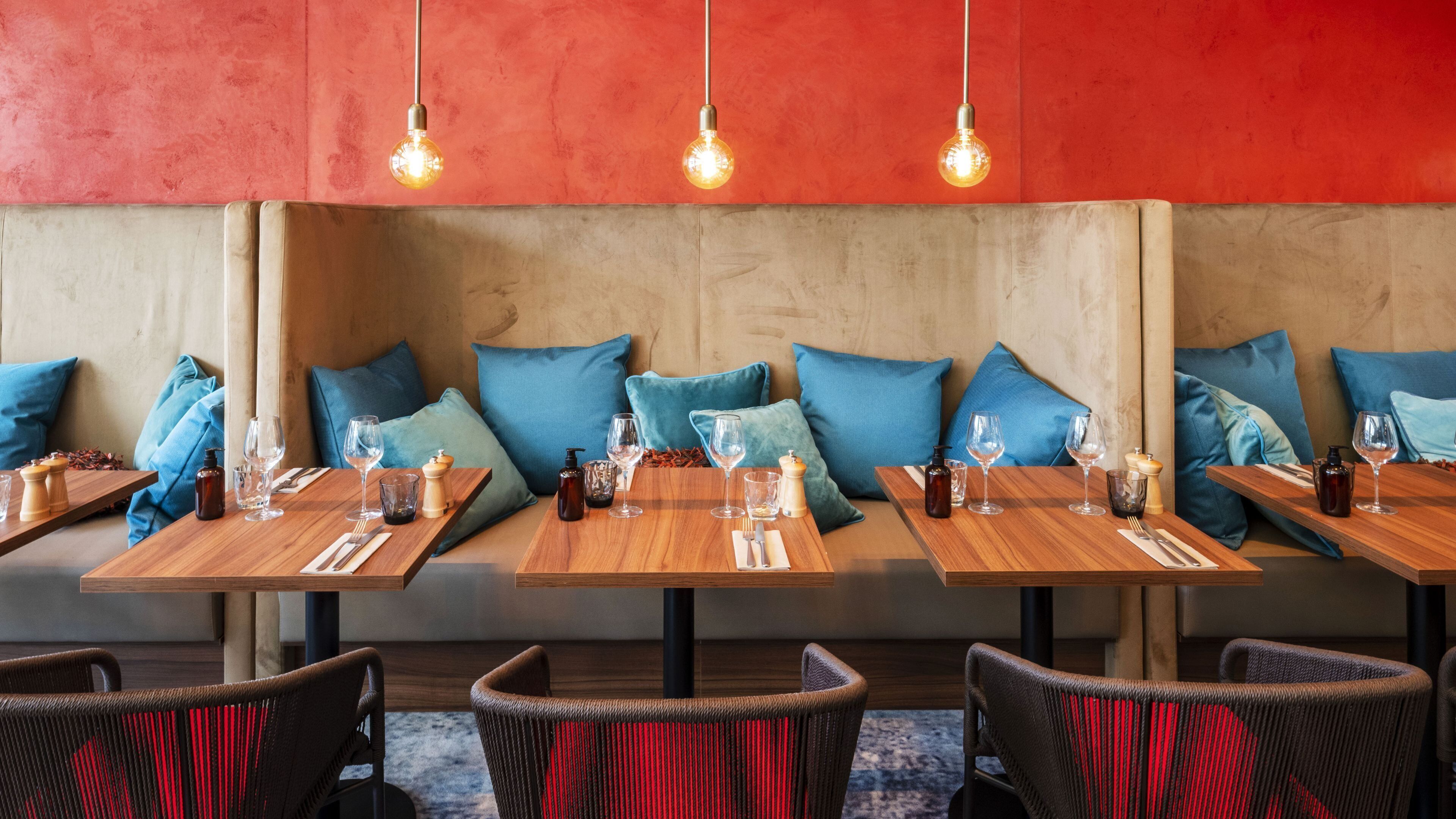 Un restaurante con mesas de madera y asientos acolchados azules.