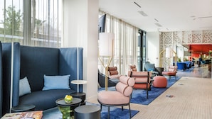 Un hall d’hôtel moderne avec un canapé bleu, un espace salon et un comptoir d’accueil.