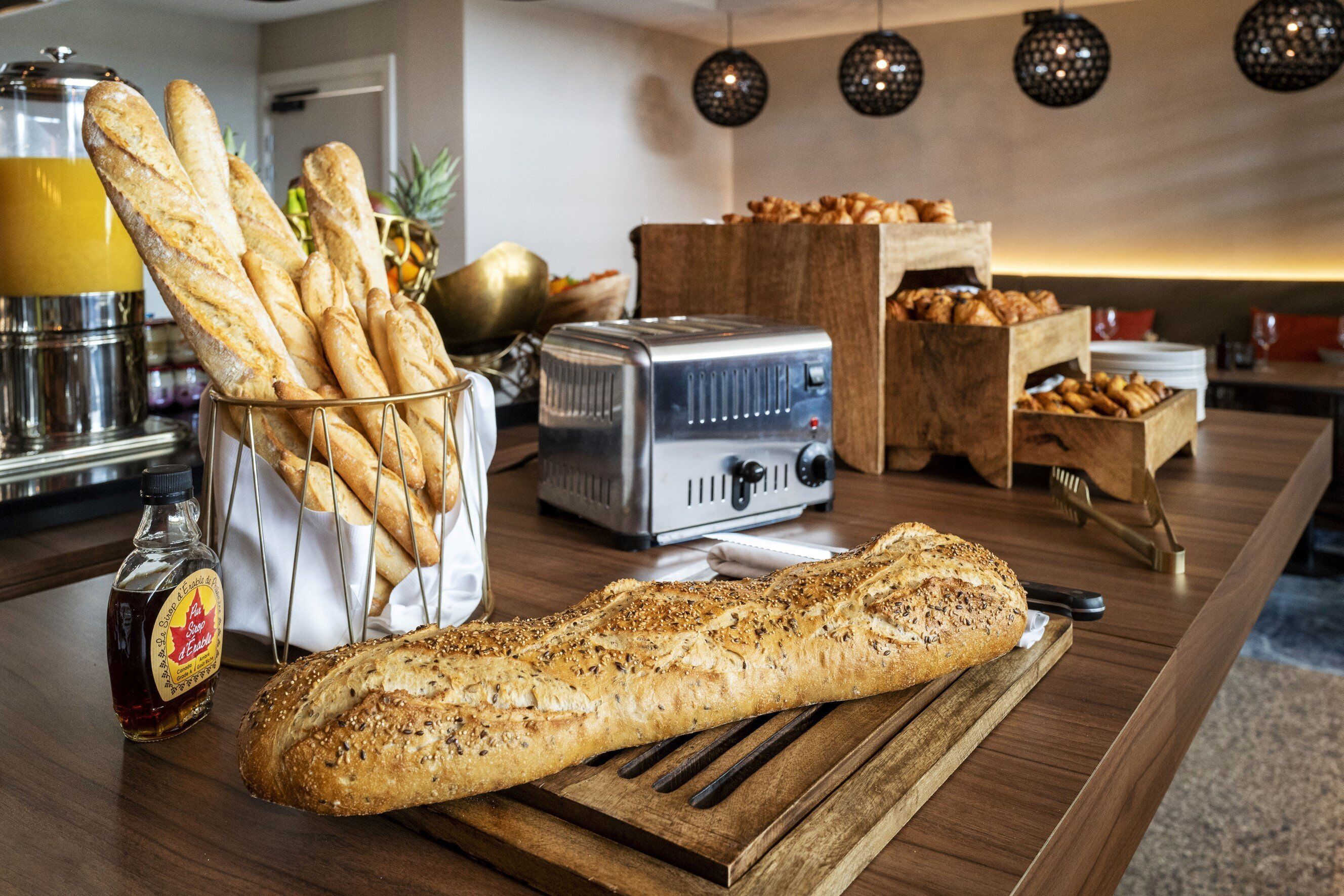 A breakfast buffet with various breads, a toaster, and condiments.