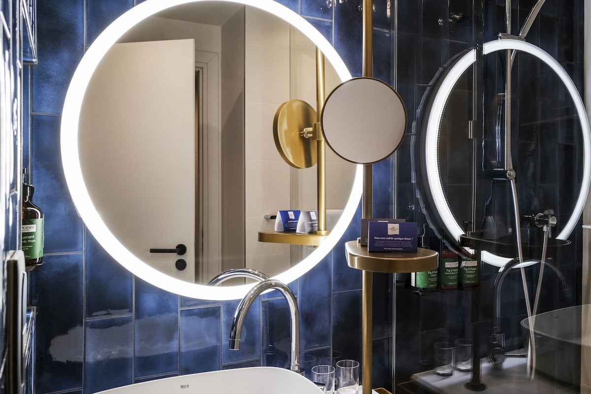 A modern bathroom with a large mirror, a round vanity, and a shower area.