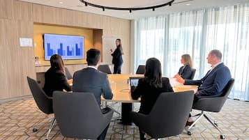 A conference room with a large table, chairs, a presentation screen, and a whiteboard.