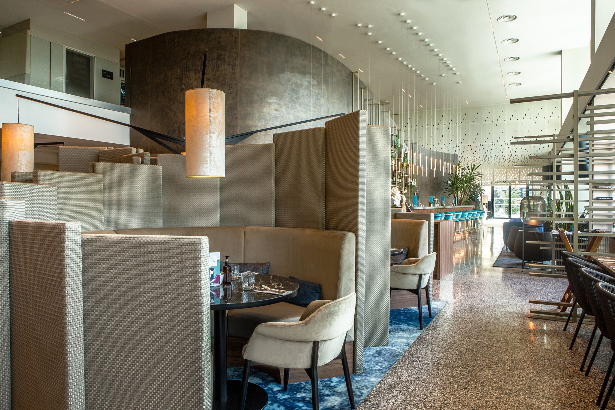 Un moderno vestíbulo de hotel con una pared curva, zonas de estar y un bar.