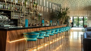 Un espace bar doté d’un long comptoir, de tabourets et d’étagères remplies de bouteilles et de verres.