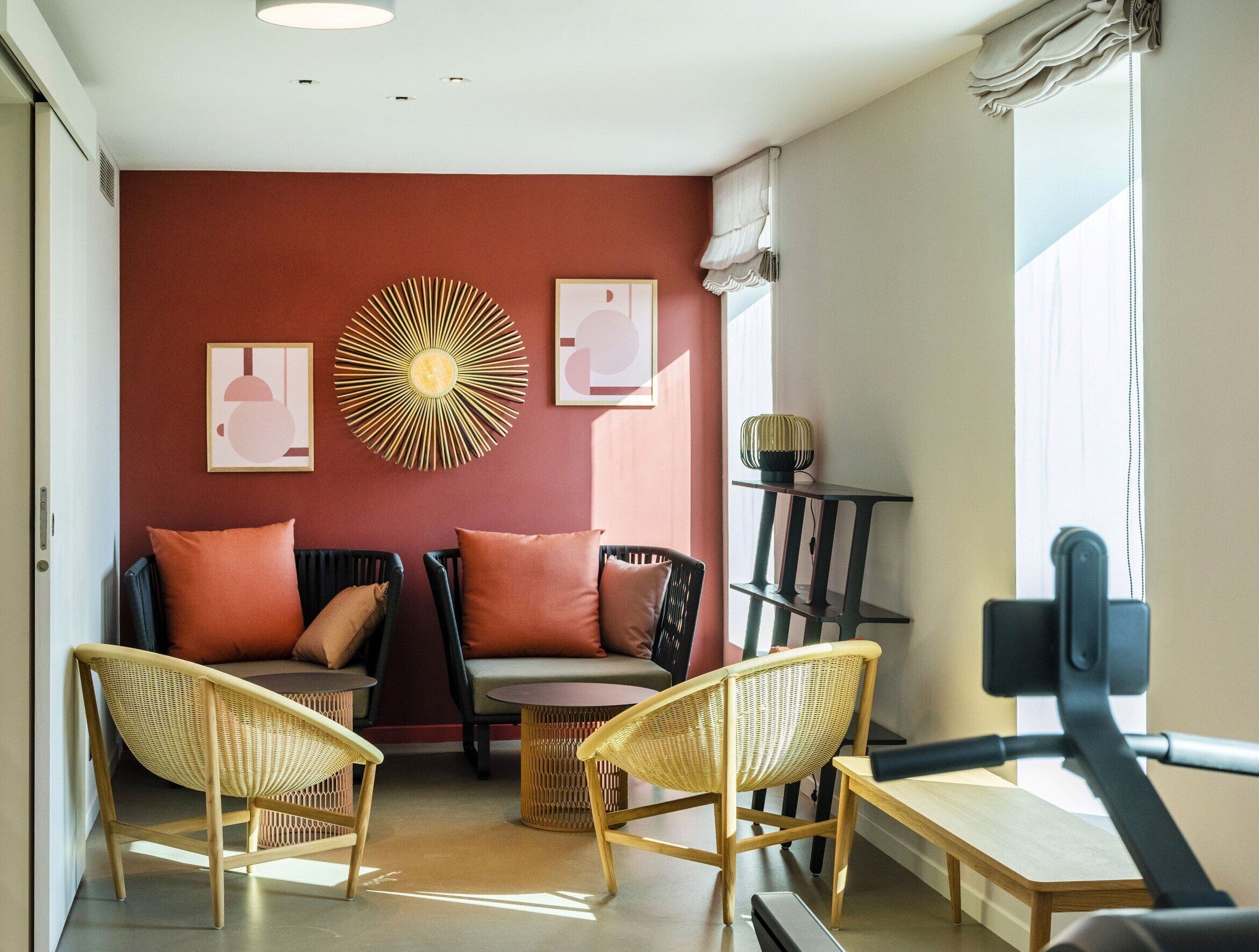 Una sala de estar moderna con dos sofás, dos sillas de mimbre, una mesita redonda y una gran decoración en la pared.