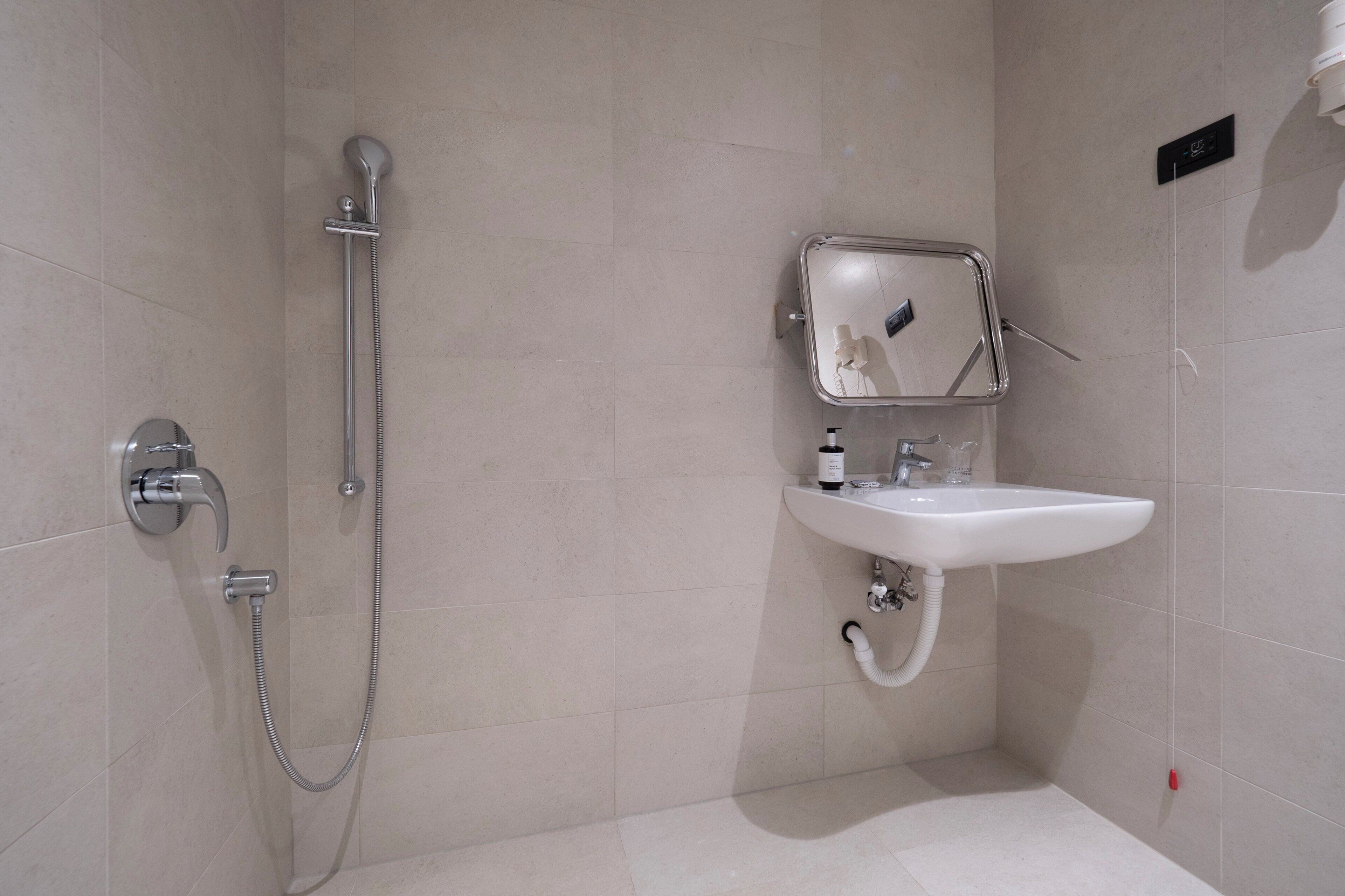 Ein modernes Badezimmer mit Dusche, Waschbecken und Spiegel.