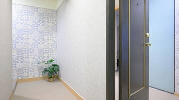Corredor com azulejos estampados, um vaso de planta e uma porta com puxador dourado.