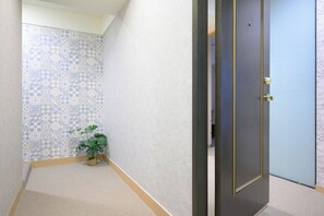 A hallway with patterned wall tiles, a potted plant, and a door with a golden handle. - 4B4b Three Suites 1 Min to Blue Line MRT (Taipei)