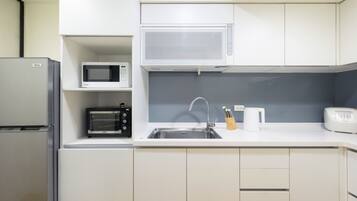 Cozinha compacta com geladeira, micro-ondas, torradeira, pia e cafeteira.