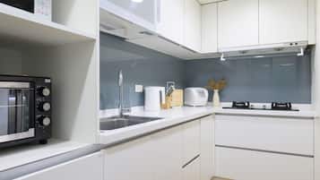 A modern kitchen with white cabinets, a microwave, a toaster, and a sink.