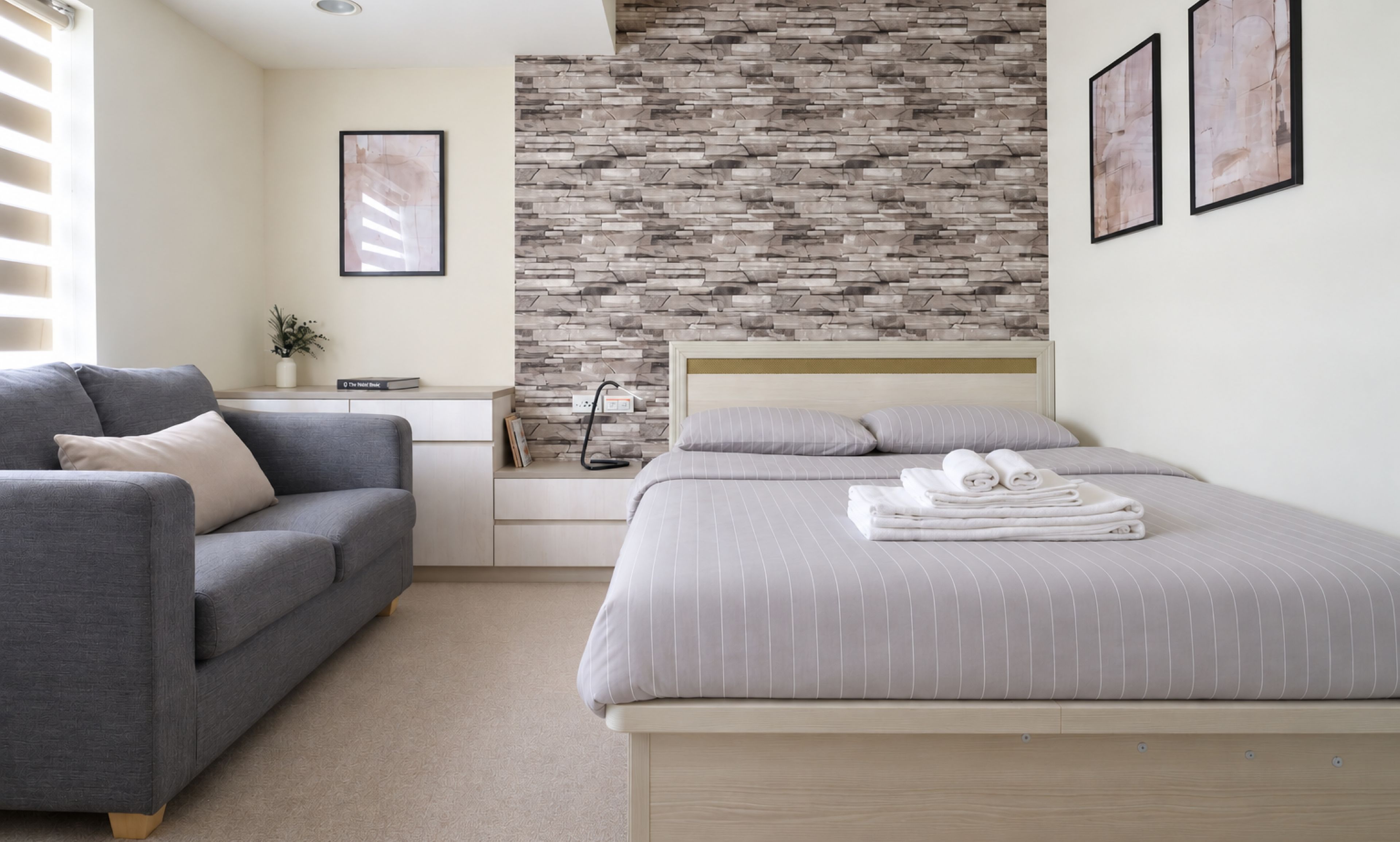 Bright ensuite bedroom with cozy sofa and stylish feature wall