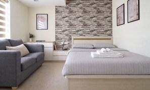 Bright ensuite bedroom with cozy sofa and stylish feature wall