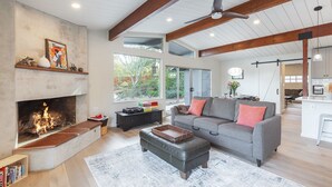 A spacious living room with a fireplace, a gray sofa, and a wooden ceiling.
