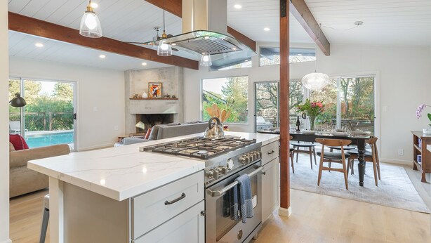 A spacious kitchen with a large island, a dining area with a view, and a fireplace.