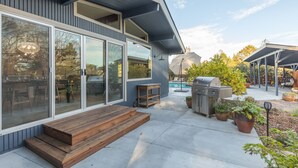 A modern house with a patio, a pool, and outdoor furniture.