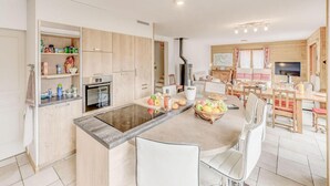 A modern kitchen with an island, built-in appliances, and a dining area with wooden furniture. - Chalet, terrace, fireplace or stove, parking, tv, ski locker, 160m², Champagny-en-Vanoise (Champagny-en-Vanoise)