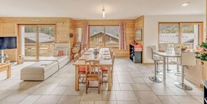A spacious living room with a sofa, a dining table set for four, and a kitchen area with a bar.