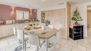 A modern kitchen with a dining area, featuring a wooden cabinet, a small Christmas tree, and a fruit bowl on the table. - Chalet, terrace, fireplace or stove, parking, tv, ski locker, 160m², Champagny-en-Vanoise (Champagny-en-Vanoise)