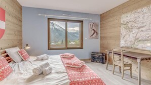 A bedroom with a bed, pillows, a desk, and a large window with a mountain view. - Chalet, terrace, fireplace or stove, parking, tv, ski locker, 160m², Champagny-en-Vanoise (Champagny-en-Vanoise)
