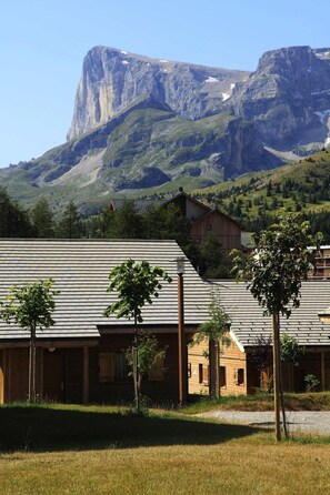 A rustic lodge with a metal roof and wooden walls, set against a backdrop of a mountain and a clear sky.